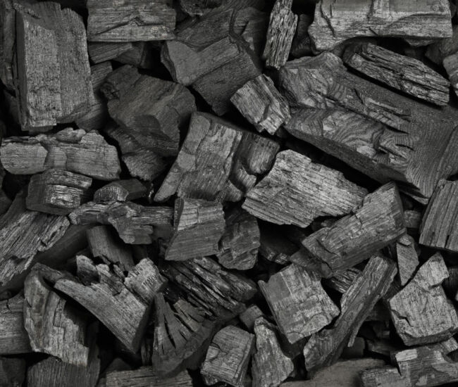 Close up background texture of many black lump charcoal pieces ready for barbecue grill, elevated top view, directly above